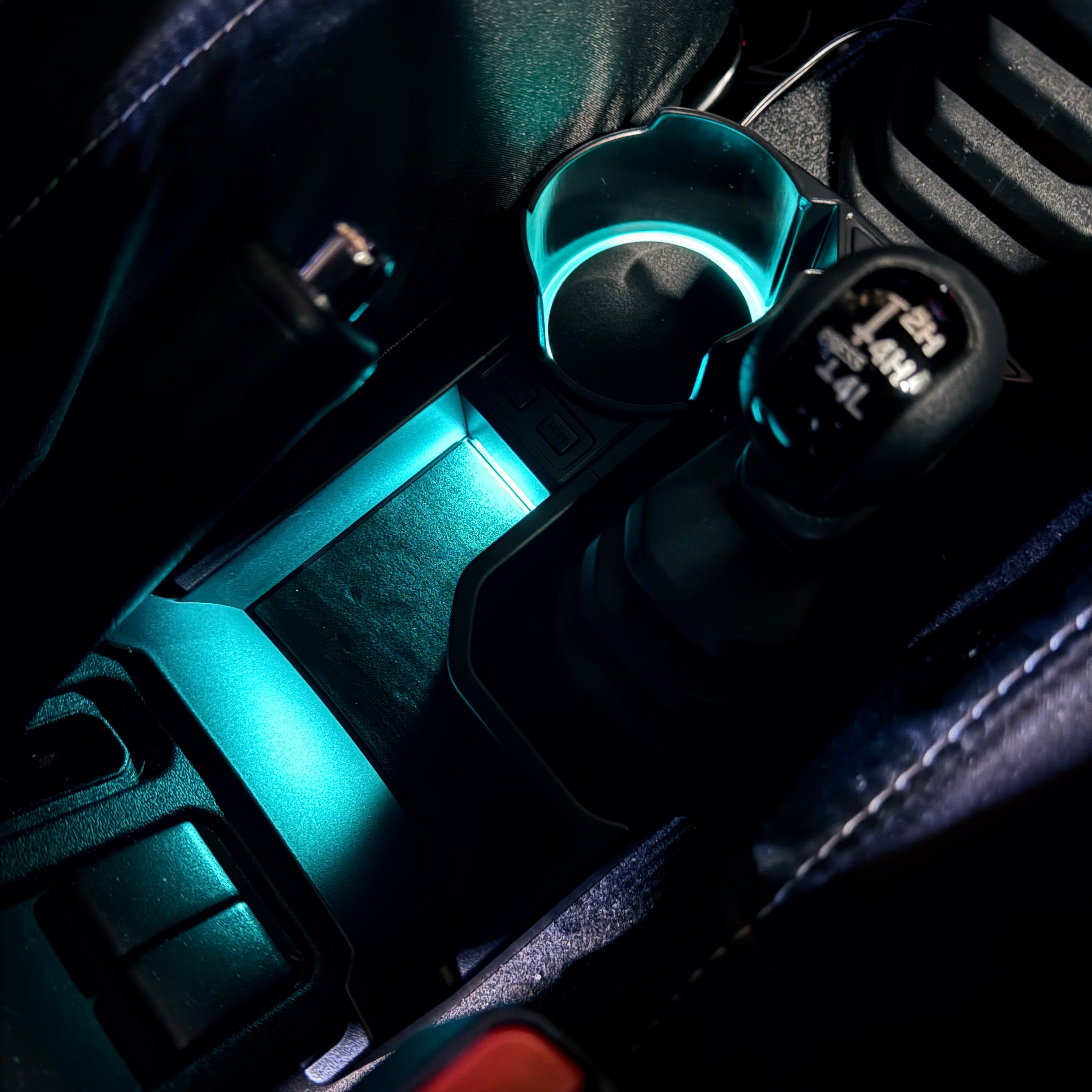 Car cup holder with a glowing blue light inside, dark interior background